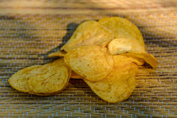 Slices of potato chips on a wooden background. Fried potatoes