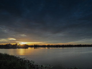 Lake view morning of yellow sun light with cloudy sky, sunrise at Krajub reservoir, Ban Pong District, Ratchaburi, Thailand.