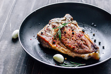 Piece of fried meat with rosemary and garlic in a pan close up