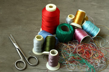 Scissors, tangled colored threads and spools.