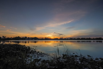 Fototapeta premium Lake view morning of yellow sun light with cloudy sky, sunrise at Krajub reservoir, Ban Pong District, Ratchaburi, Thailand.