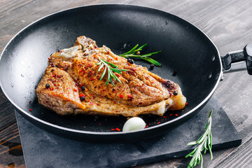 Piece of fried meat with rosemary and garlic in a pan close up