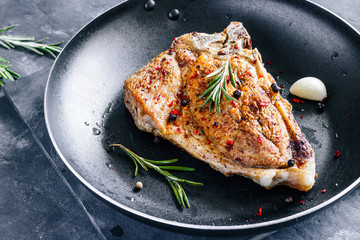 Piece of fried meat with rosemary and garlic in a pan close up