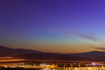 beautiful landscape late at the evening, stunning view on mountains from the city with glowing street lights in the foreground and on the mountain