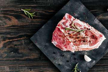 Raw piece of pork meat with rosemary and garlic dark style photo