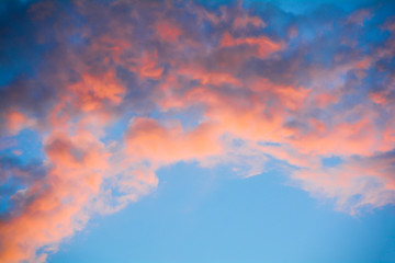 The clouds in the blue sky are illuminated by the orange setting sun. Natural background.