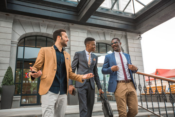 three young friendly men in suits near the building
