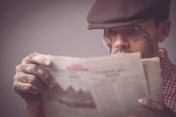 News and press concept.  Handsome hipster man  in fashionable retro styled wear after workreads a newspaper.