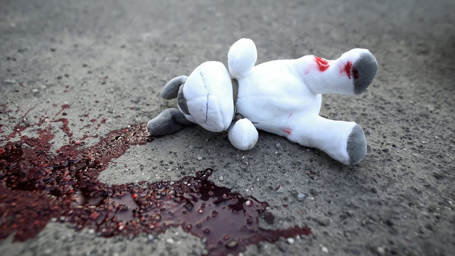 Dirty toy dog lying on road near blood stain, terrible car accident with victims