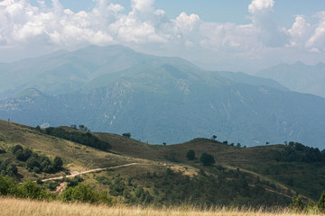 Obraz premium mountain meadow with trees, mountain view, white clouds, mountain road, summer, sunny