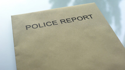 Police report, folder with important documents lying on table, investigation