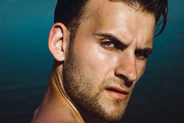 Portrait of handsome young man posing on the beach. Perfect hair & skin. Outdoor shot.