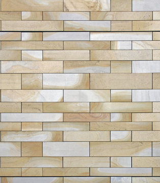 full frame image of a wall made of large flat blocks of yellow and grey york stone with a marbled texture