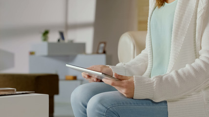 Woman watching video on tablet, comfortably sitting on couch, modern technology