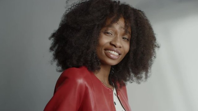 Attractive Black Girl with Lush Curly Hair Posing for a Fashion Magazine Photoshoot. Girl Smiles Playfully, Acts and Plays with Facial Expressions. Photoshoot in Professional Studio. Portrait Shot