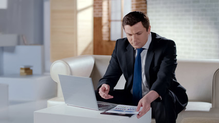 Fototapeta na wymiar Young businessman checking financial report, working on laptop in modern office
