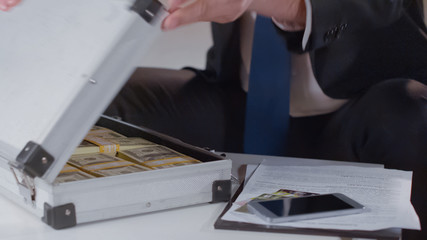 Businessman checking money in briefcase, kickback for politician, close up