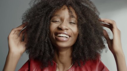 Attractive Black Girl with Lush Curly Hair Posing for a Fashion Magazine Photoshoot. Girl Smiles Playfully, Acts and Plays with Facial Expressions. Photoshoot in Professional Studio. Portrait Shot