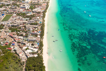 Island Boracay, Philippines, view from above. White beach with palm trees and turquoise lagoon with boats. Buildings and hotels on the big island.