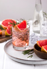 Grapefruit cocktail with rosemary on white wooden table