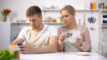 Jealous woman peeping in husbands smartphone, relationship crisis, distrust