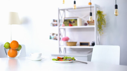 Cup of coffee and fresh salad with vegetables and greens in white plate on table