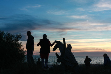 evening sea and dune view with people silhouettes, nature, parched tree silhouette, sky with clouds, summer