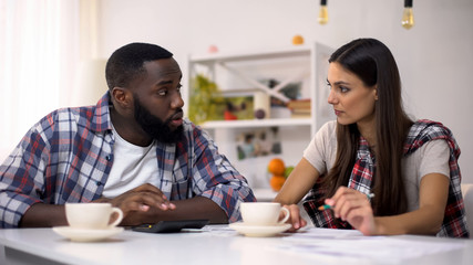 Black man and young lady planning family budget, counting incomes and expenses
