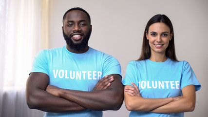Mixed-race volunteers standing with hands crossed in rehabilitation center, help