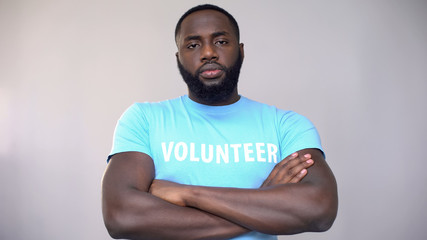 Serious Afro-American volunteer standing with hands crossed, altruistic activity