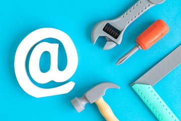 Flat lay of construction tool toys and email sign against blue background minimal creative concept.