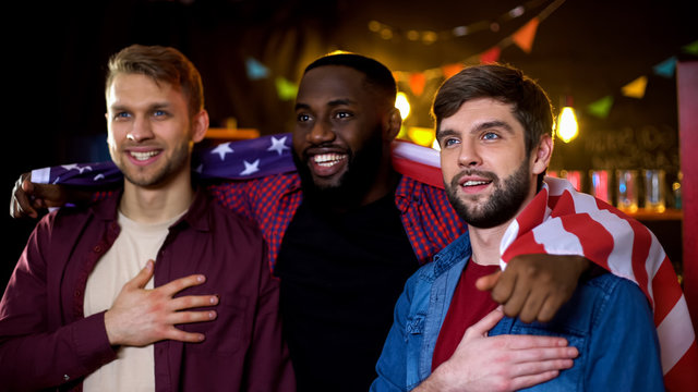 American Friends Wrapped In National Flag Watching Election Results On Tv