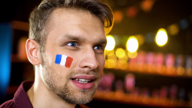 Bearded man with painted flag of france watching world tournament in bar - Powered by Adobe