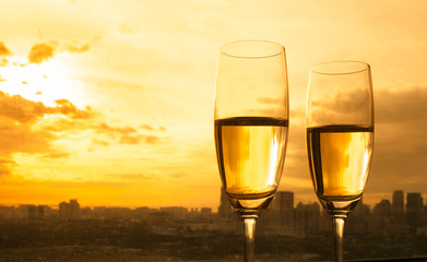 two glasses of champagne on sunset city background 