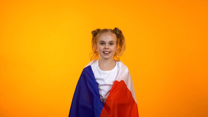 Cute girl with french flag on shoulders cheering for favorite team, football