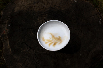 above view of cappuccino cup drink with milk foam drawing of leaf on dark wooden  background