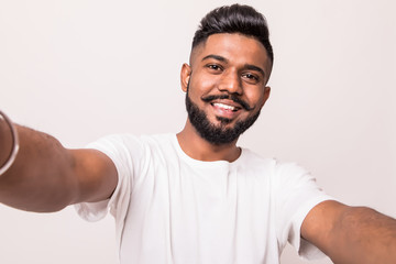 Young pretty indian man taking selfie isolated on white background