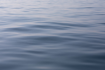 Tranquil and serene ocean surface. Calm and relaxed mirror-like blue sea background.