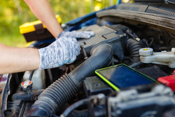 Hands of mechanic repairing the engine of the special keys (wrenches and ratchets). Professional car mechanic in gloves working on the side of the road, field service.