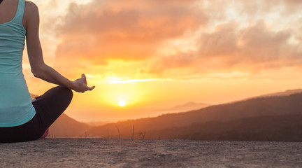 Fototapeta premium woman practicing yoga on a mountain at sunset