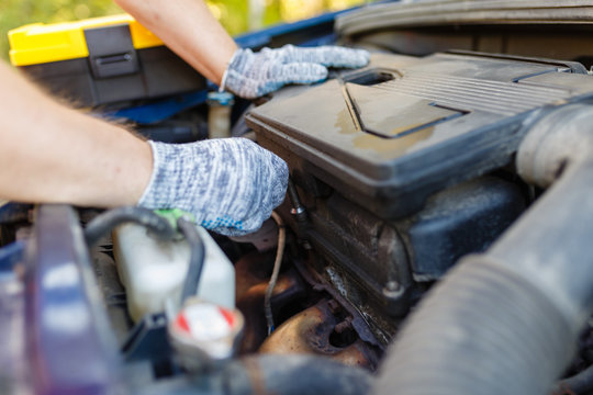 Hands of mechanic repairing the engine of the special keys (wrenches and ratchets). Professional car mechanic in gloves working on the side of the road, field service.