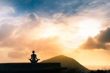 Naklejka na ściany i meble Peace and serenity. Female meditating outdoors up on a mountain top.