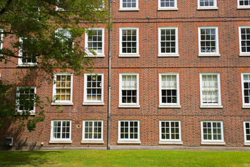 Classic historical Office Building Georgian British English style with white windows, red brick wall and garden in front