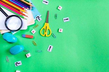 Notebooks, pencils, scissors and an eraser on a green background with copy space for text. Concept of study and school. Flat lay
