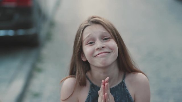 Cute teenage girl begging for favor. Close-up footage from above. Nice little lady looking at camera. Mimic. Outdoors, magnificent, marvelous, splendid, stunning, wonderful