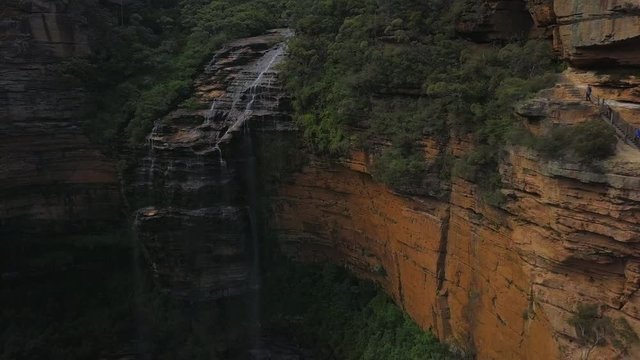 Aerial Pan: Hiking on Cliff Wall next to Beautiful Waterfall, Blue Mountains, Australia