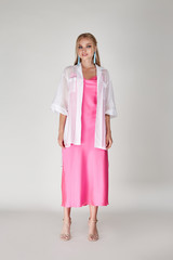 Pretty woman beautiful face bright makeup long blond hair fashion model wear trend clothes for date party summer walk travel cruise collection organic silk cotton dress accessory jewelry white studio.