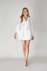 Pretty woman beautiful face bright makeup long blond hair fashion model wear trend clothes for date party summer walk travel cruise collection organic silk cotton dress accessory jewelry white studio.