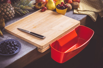 Chopping Board with Red Waste Container with Fresh Fruits Background