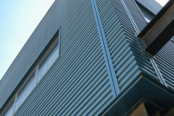 Blue metal exterior siding of a building. - obrazy, fototapety, plakaty